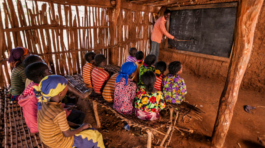 African children during english class in very remote school. The bricks that make up the walls of the school are made of clay and straw. There is no light and electricity inside the classroom