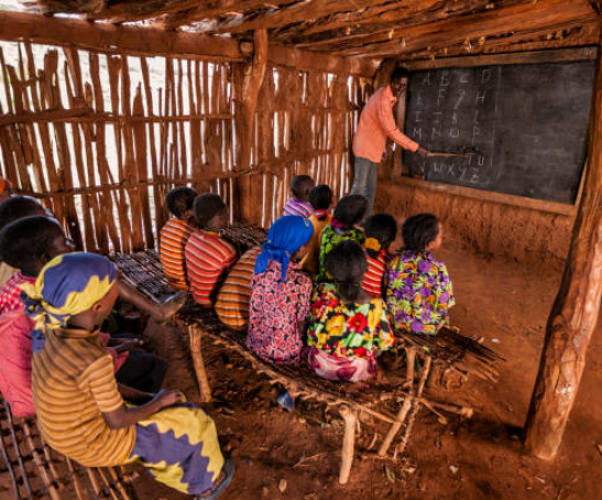 African children during english class in very remote school. The bricks that make up the walls of the school are made of clay and straw. There is no light and electricity inside the classroom