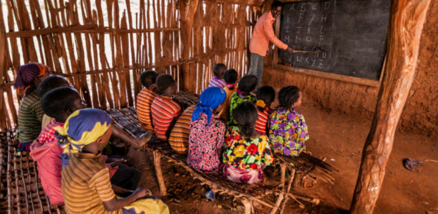 African children during english class in very remote school. The bricks that make up the walls of the school are made of clay and straw. There is no light and electricity inside the classroom
